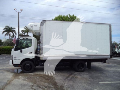 Truck side view showing a refrigerated box on a white cab with a white bird graphic overlay over the image.