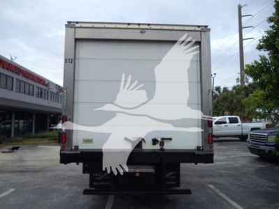 Rear view of a refrigerated box truck with plain white back doors, some equipment beneath, and a faint watermark of a white bird graphic overlay.