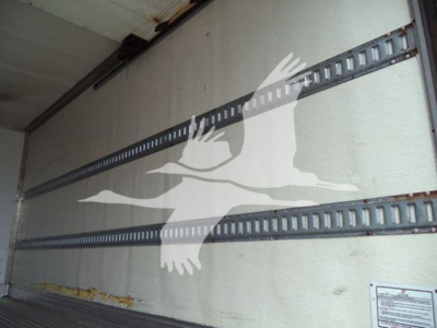 Interior of a refrigerated truck trailer with metal horizontal E-track rails and a white bird logo overlay on the side; no legible text visible.