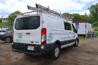 Ford Transit 350 cargo van with ladder rack, rear doors, and service decals visible.