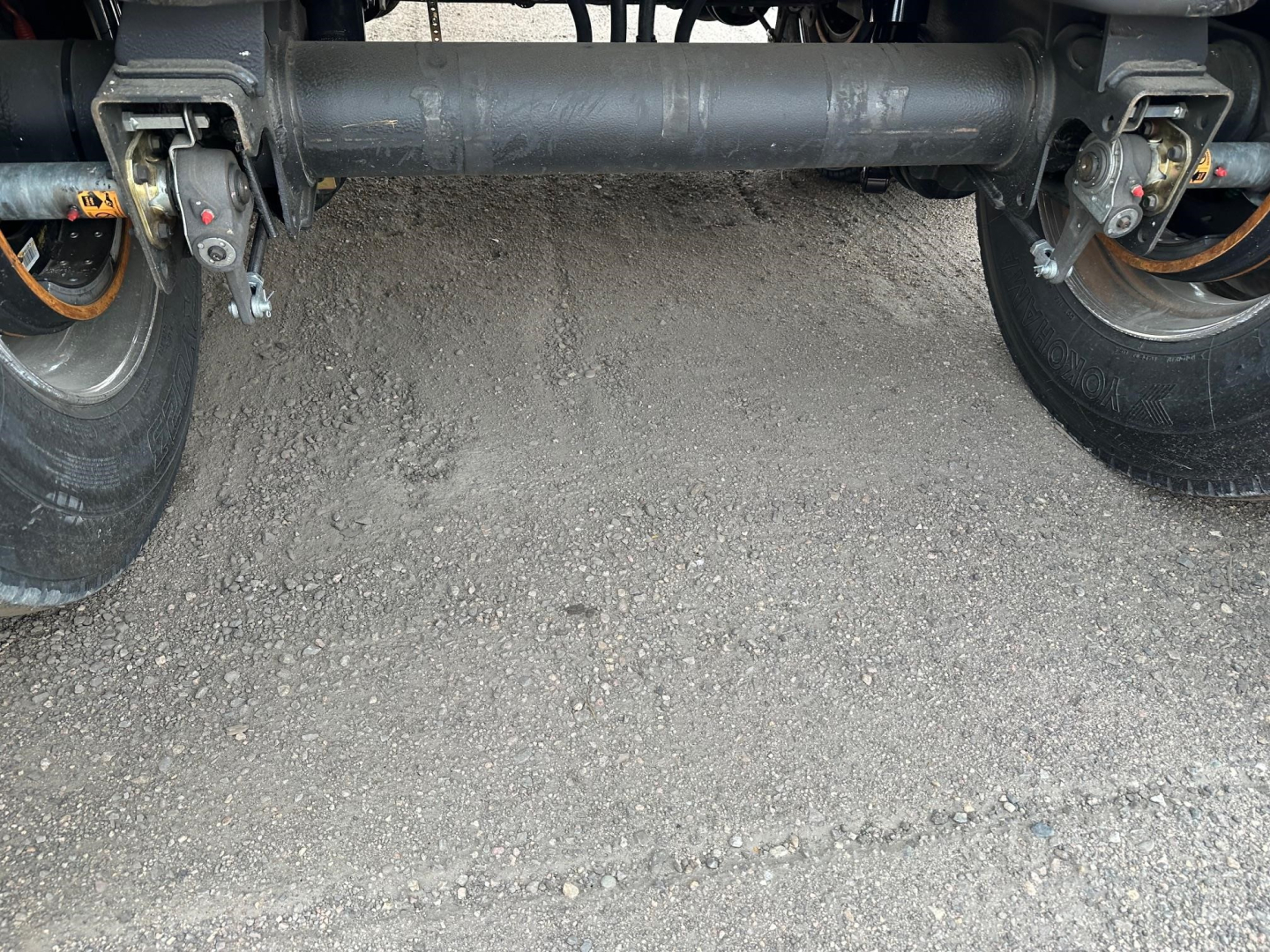 Mac light weight aluminum end dump trailer undercarriage showing steel axle beams and suspension with wheels and tires