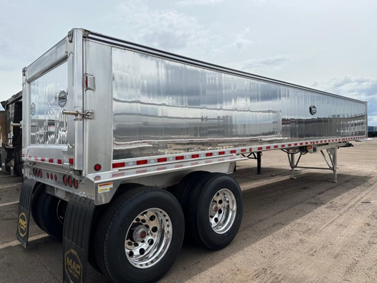 Mac Western light weight aluminum end dump trailer, tandem axles, polished aluminum sides, rear gate, LED lights, reflective tape along sides.