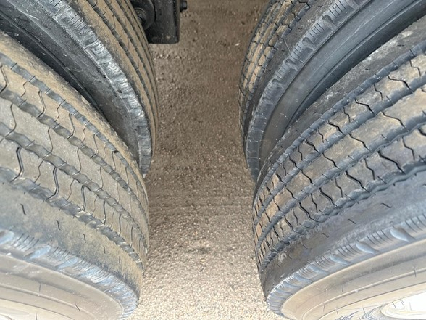 Dual rear trucks tires on Mac Western light weight aluminum end dump trailer showing tread and dirt surface