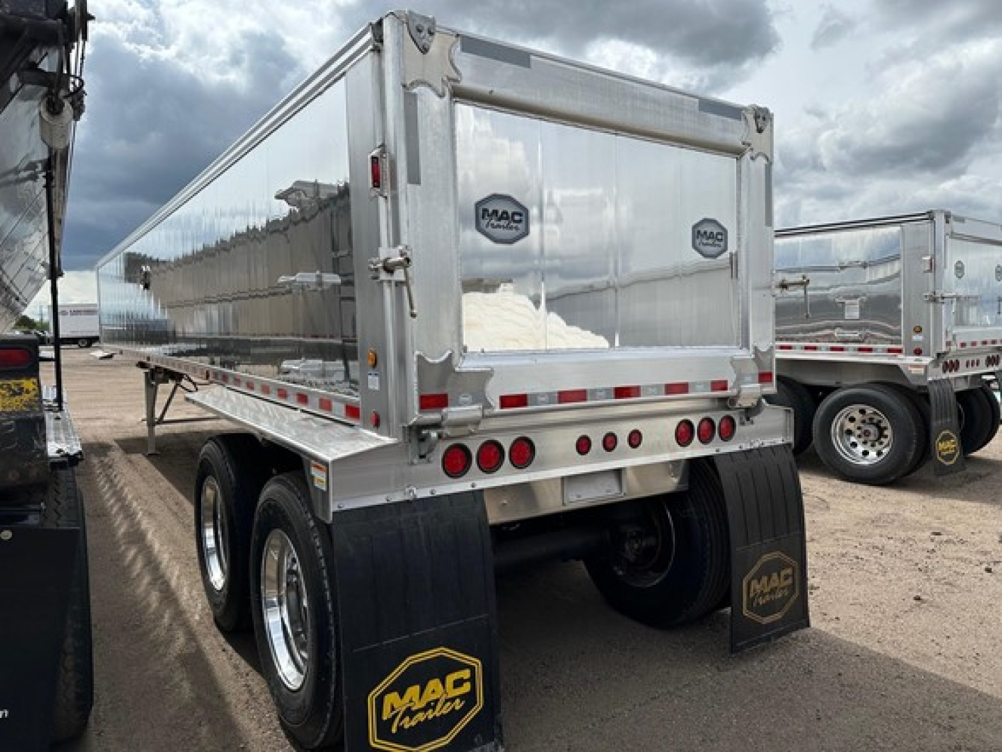 Mac Western light weight aluminum end dump trailer showing rear end with MAC trailer logos and dual axles with black mud flaps.