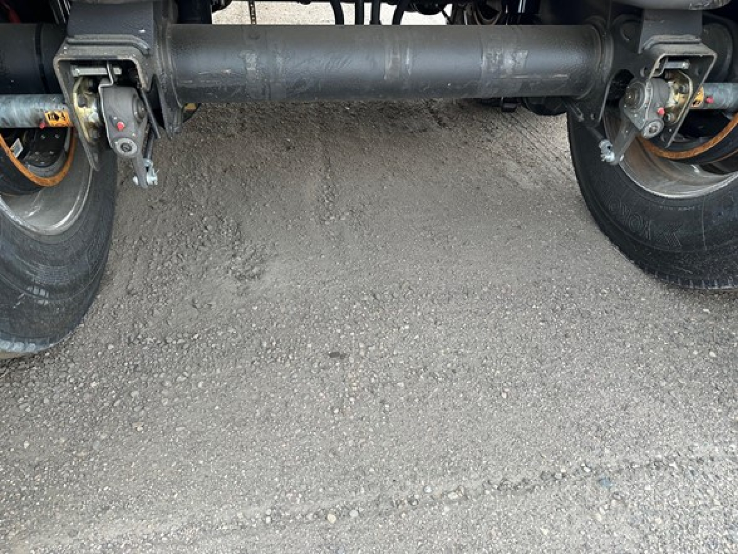Rear view of a 2026 Mac Western lightweight aluminum end dump trailer showing the tandem axle supports and transfer hitch with wheels visible.
