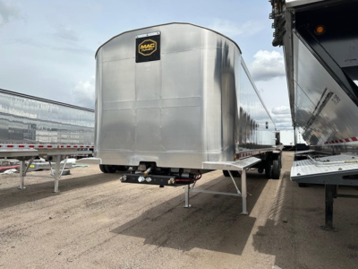 Mac trailer with curved aluminum end dump body, front view showing Mac logo on the nose, stabilized legs, and underside components.