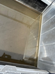 Dump trailer interior with wooden floor and metal side walls; light reflects off smooth surface.