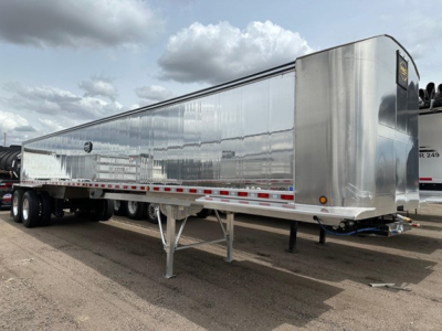 Aluminum end-dump trailer on a truck chassis with polished alloy finish, dual rear axles, and load cover area; side rails and landing gear visible.