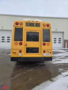 Rear view of a yellow school bus with 'SCHOOL BUS' sign, emergency door, and taillights.