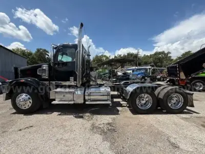 Freightliner Coronado day cab tractor seen in side profile with chrome fuel tanks and dual rear axles.