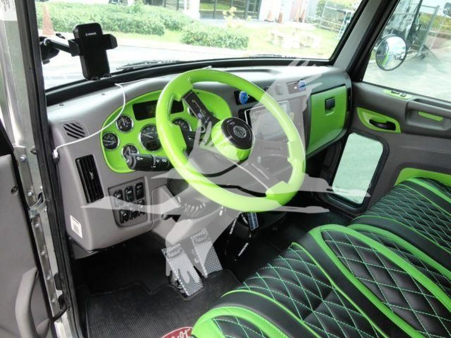 Truck cockpit with lime green steering wheel and matching lime green accents on dashboard and seats. Instrument cluster, pedals, and door panels visible in cab interior of a 2020 Peterbilt 337.