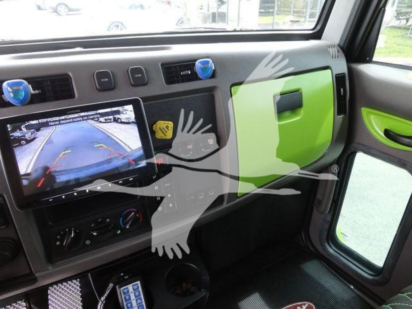 Instrument panel and dashboard of a 2020 Peterbilt 337 truck interior with a backup camera display and green accents.