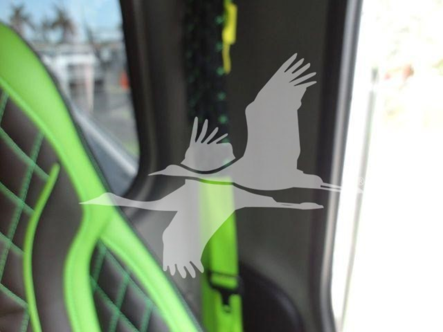 Truck interior window view with green seat accents and a silhouette of birds in flight against the glass.