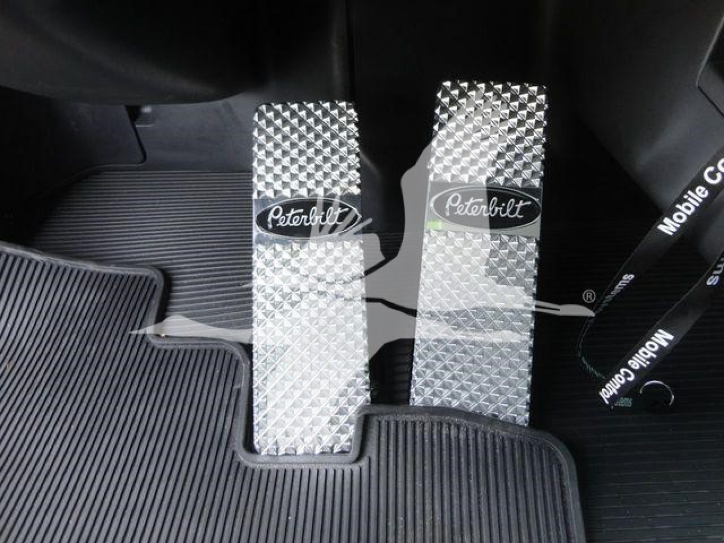 Pedals in a Peterbilt 337 interior showing metal anti-slip pedals with Peterbilt logos.