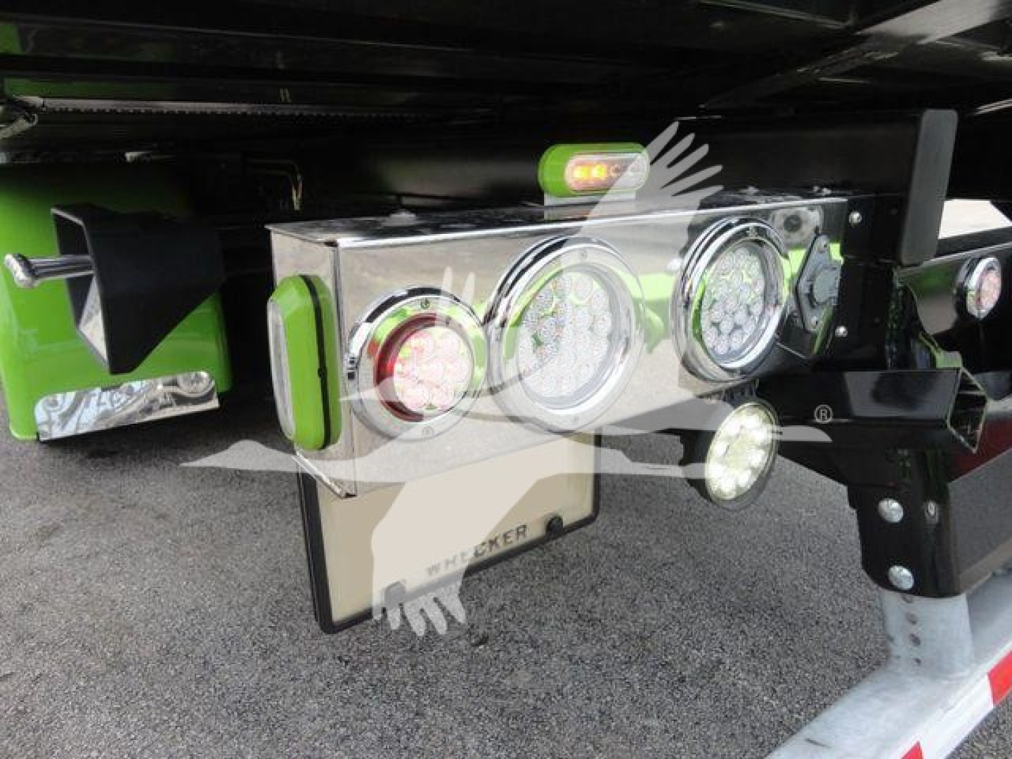 Triple round LED tail/marker lights and chrome toolbox on Peterbilt 337 rollback truck, with green accents and visible license-light area.