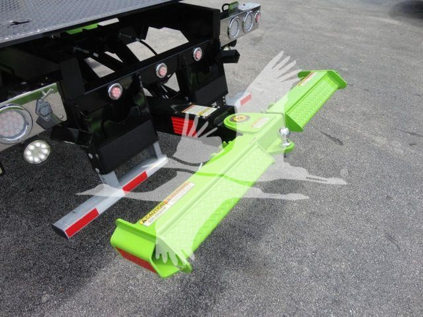 Green front-mounted implement hitch on a Peterbilt 337 rollback truck, with bright lime green bar and mounting hardware attached to rear of vehicle.