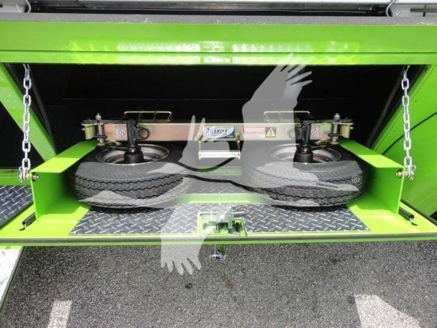 Peterbilt 337 rollback truck storage compartment with two spare tires and hydraulic leveling mechanism visible inside green compartment.