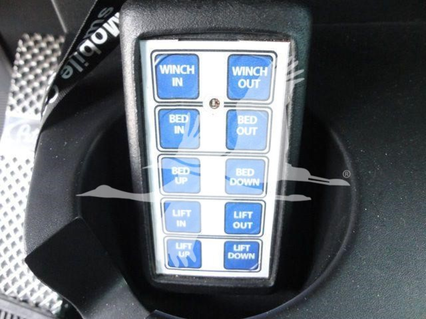 Truck control pendant showing buttons labeled Winch In, Winch Out, Bed In, Bed Out, Bed Up, Bed Down, Lift In, Lift Out, Lift Up, Lift Down.