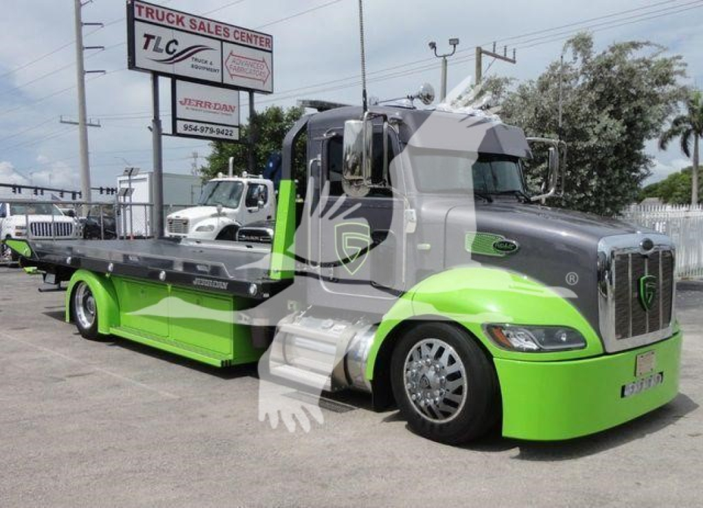Peterbilt 337 tow truck with lime green lower cab and gray upper cab, rollback bed, dealership sign in background.
