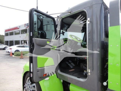 Truck cab interior visible through open door of a green Peterbilt 337 rollback truck with side steps and dashboard visible.