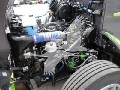 Peterbilt engine bay with blue intercooler hose and various hoses, wiring, and components visible; front wheel and fender in view.