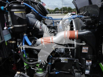 Trucks engine bay view showing blue and black hoses, exhaust components, and various labels in engine area.
