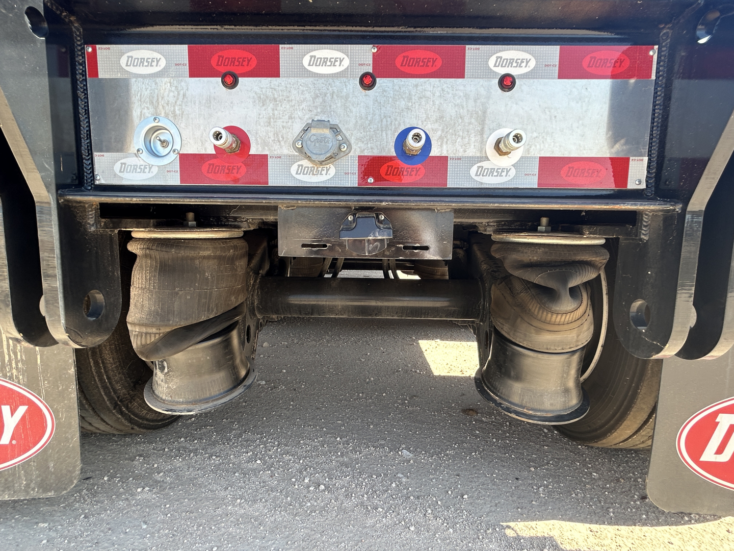 Trailer rear showing air lines and connectors with Dorsey branding, undercarriage and leaf spring suspension visible.