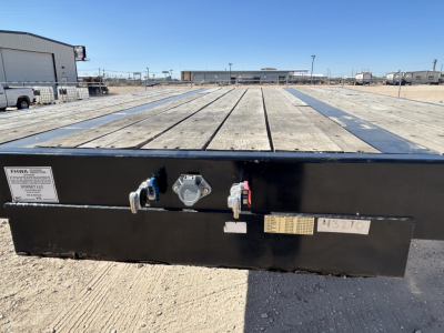 Trailer bed of a Dorsey DF48 60 Ton flatbed trailer showing rear coupler and safety lugs with labels and stickers
