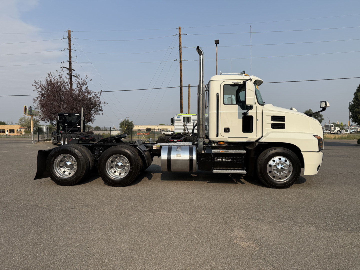 Side view of a white 2020 Mack Anthem daycab truck chassis with triple rear axles and polished wheels.