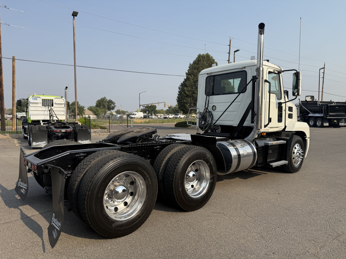 Truck rear-angled view of a white 2020 Mack ANTHEM daycab tractor showing dual rear axles, fuel tanks, exhaust stack, and cab with windows.