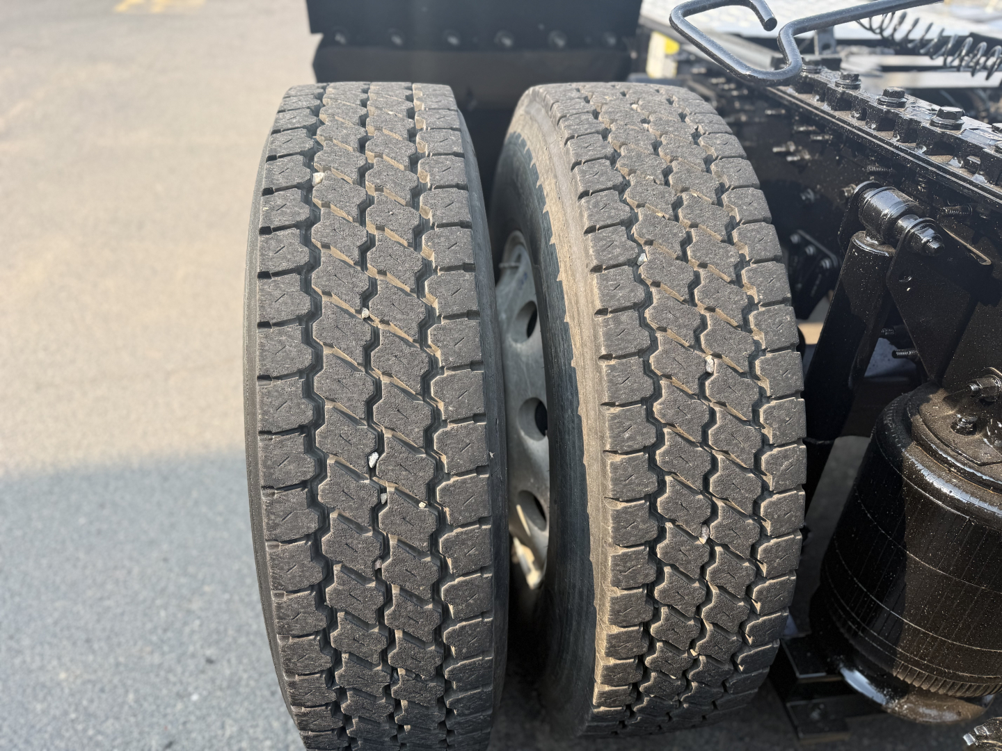 Dual rear truck tires on a Mack ANTHEM drivetrain showing tread pattern with wheel hubs and part of the frame; no legible model text visible on tires.