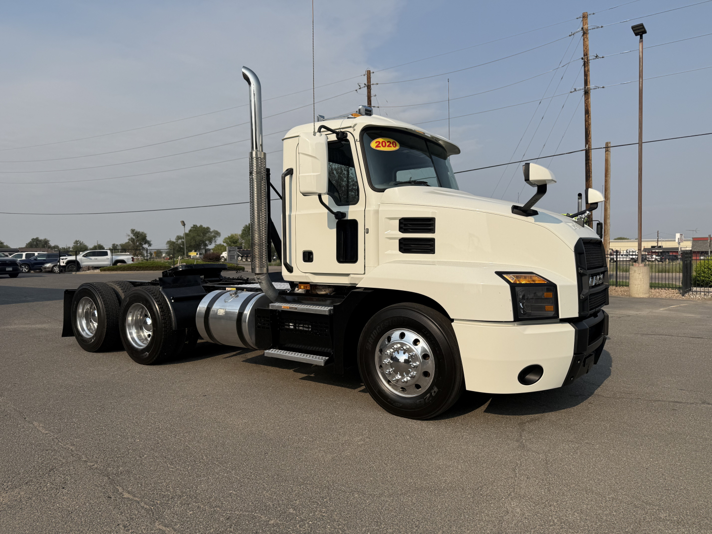 Mack Anthem 2020 conventional daycab tractor truck in light color, side view showing dual rear axles, fuel tanks, exhaust stacks, and showroom-style cab with VIN tag visible.