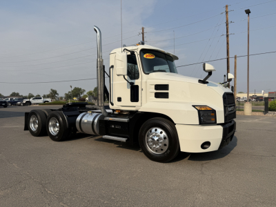 Mack Anthem 2020 conventional daycab tractor truck in light color, side view showing dual rear axles, fuel tanks, exhaust stacks, and showroom-style cab with VIN tag visible.