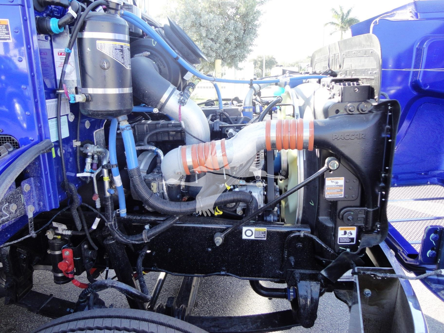 Peterbilt 337 engine bay showing large air intake, coolant reservoir, hoses, and radiator; focus on side view of cab-over area with blue paint and various components.