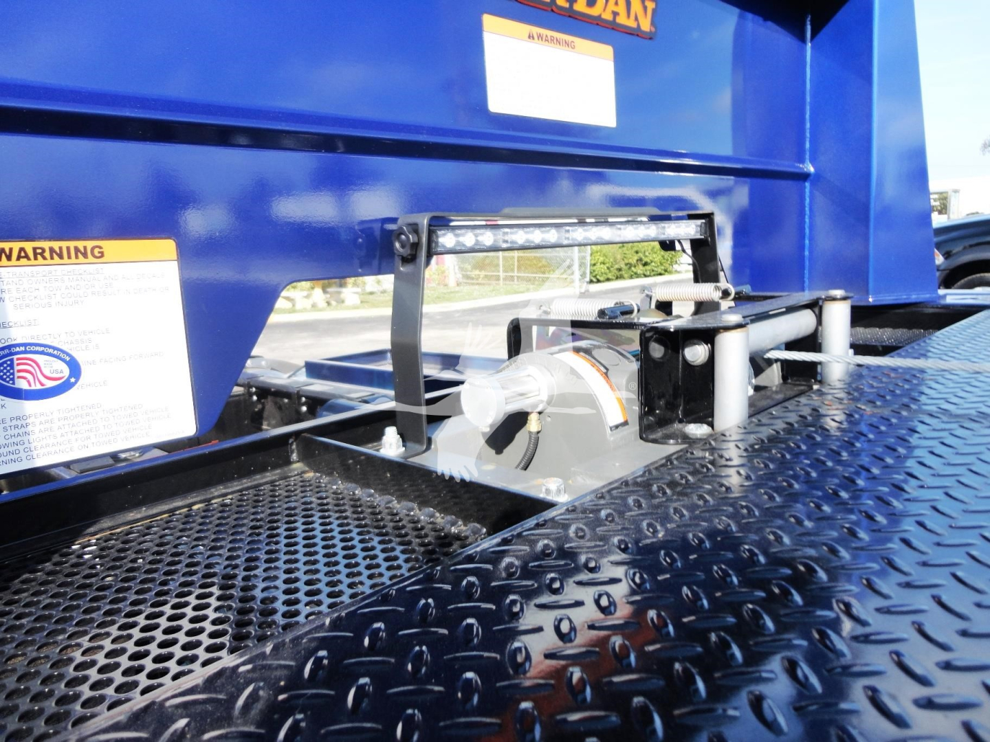 Peterbilt 337 rollback truck rear deck with mounting hardware and diamond plate surface, showing winch mechanism and safety labels.