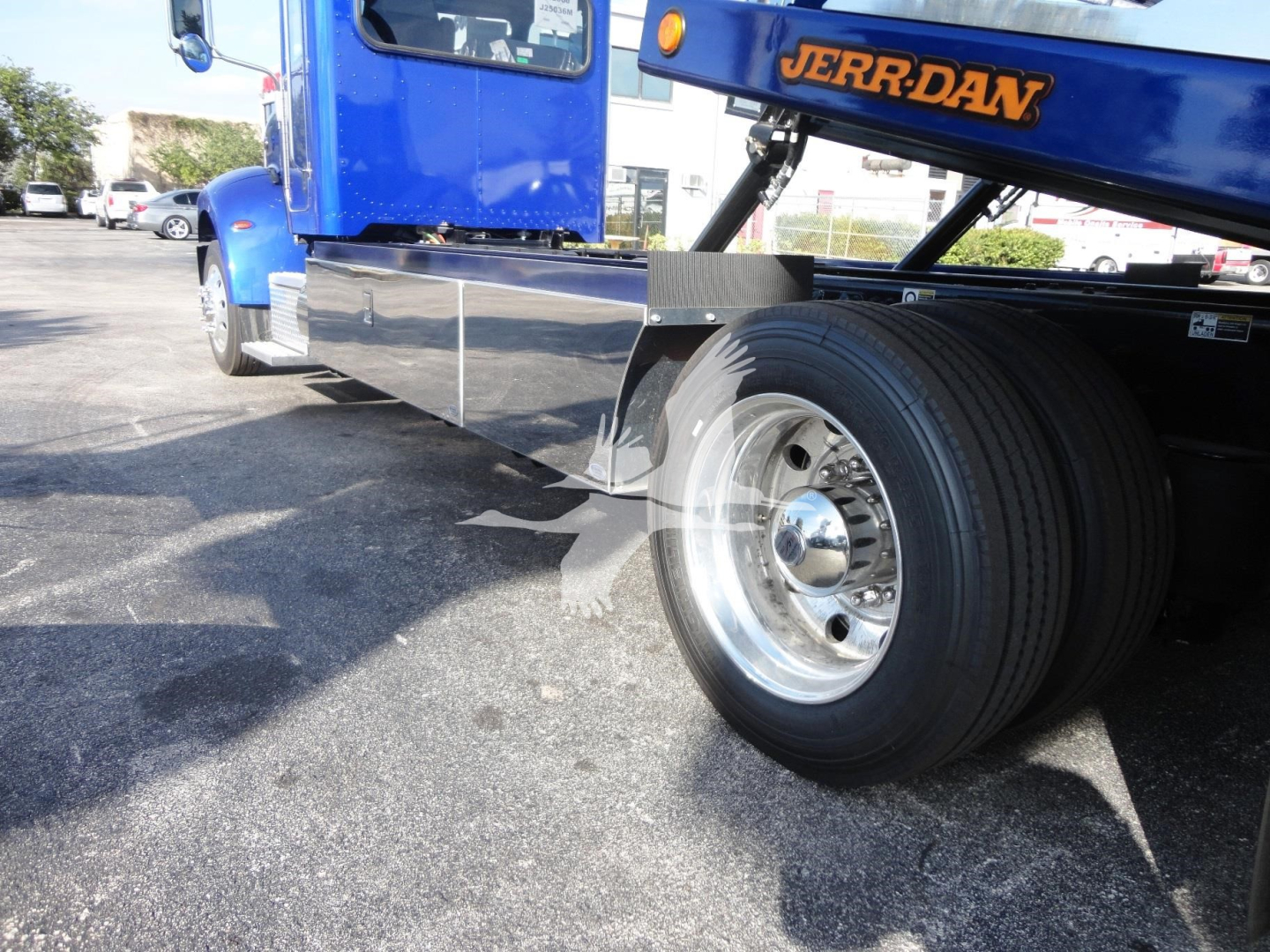 Peterbilt 337 rollback tow truck with blue cab and chrome side panels, wheel and tire visible, 'JERR-DAR' branding on lift arm.