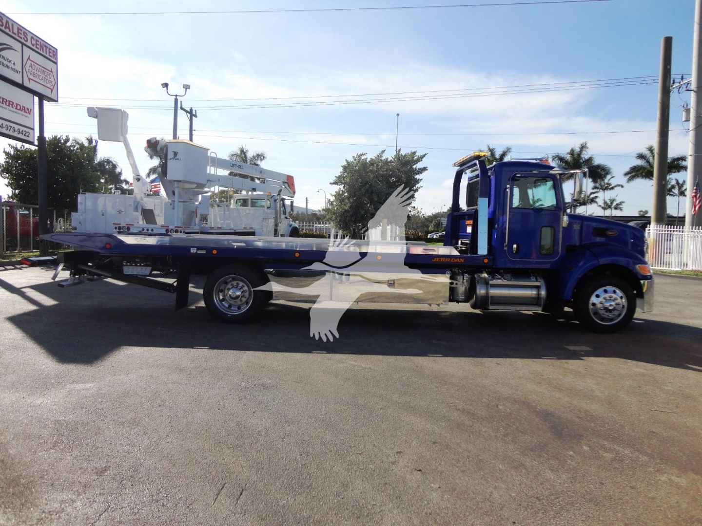 Peterbilt 337 rollback truck side view showing flatbed with equipment and blue cab.