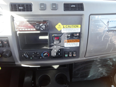Peterbilt 337 dashboard area with radio, control switches, warning stickers, and beverage cup holders visible.