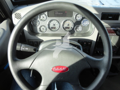 Peterbilt dashboard and steering wheel with instrument cluster and logo. Dashboard center shows gauges and digital display; steering wheel has Peterbilt emblem.