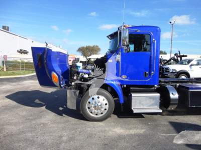 Peterbilt 337 rollback truck blue cab with hood open, showing front wheel, engine bay area, and chrome steps.