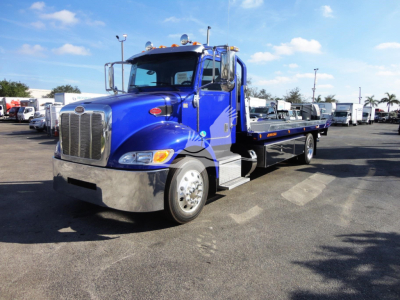Peterbilt 337 rollback tow truck in blue, front three-quarter view showing chrome bumper, grille, cab, and flatbed low-loader.