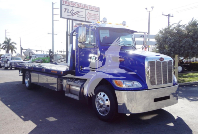 Peterbilt 337 rollback tow truck in blue with chrome bumper and flatbed, front view.