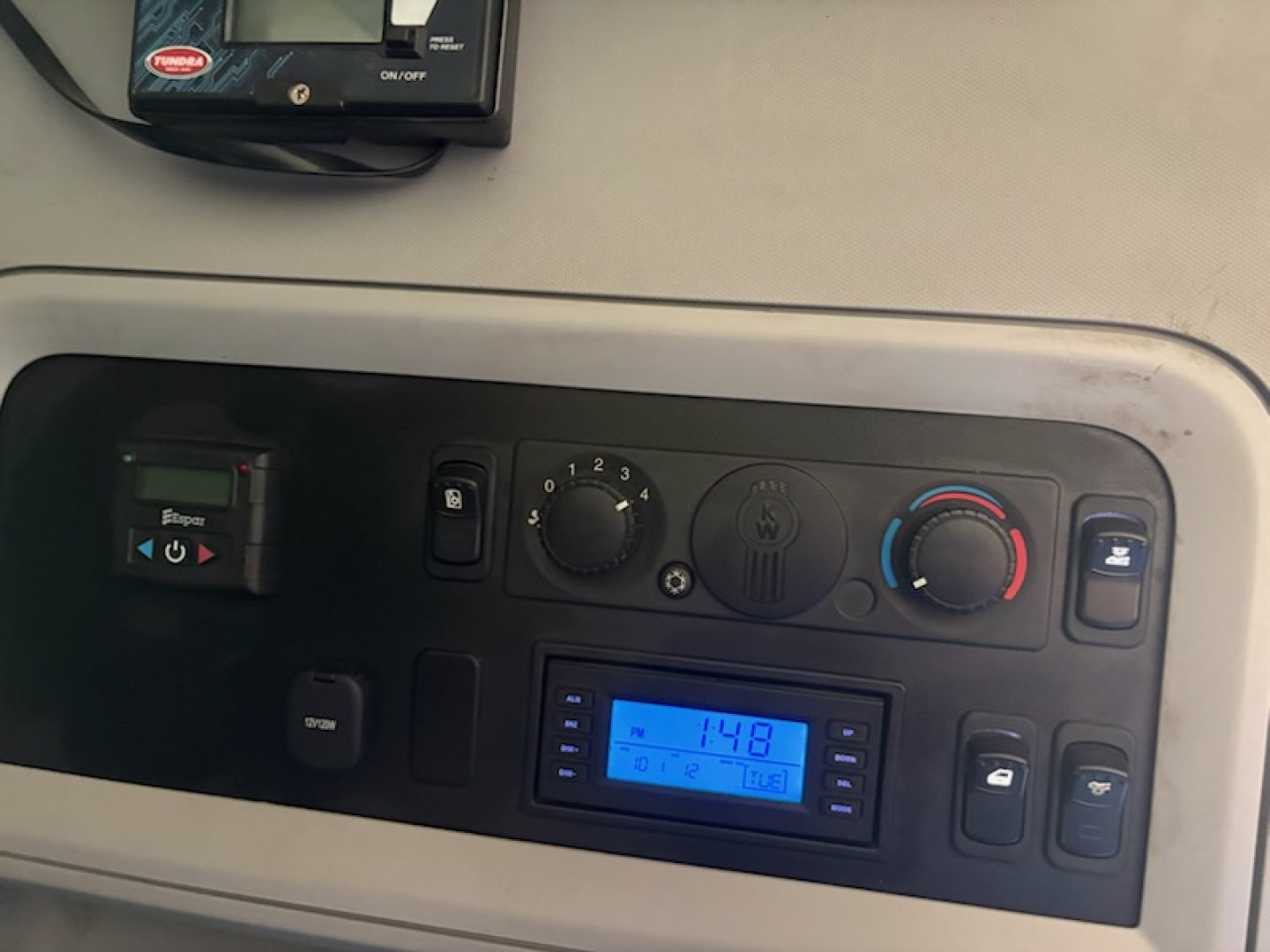 Truck cab interior dash panel showing climate controls and a blue digital display in a Kenworth T680 cab