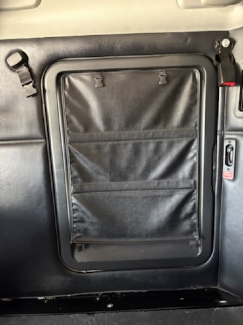 Kenworth T680 cab interior side door pocket with storage pouches and latch shown.