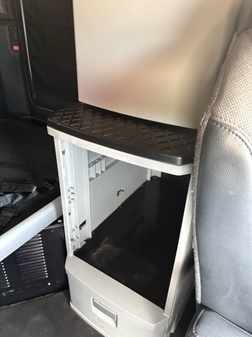 Kenworth T680 interior showing a small steps/bed area with an open storage cabinet under a black diamond-plate platform.