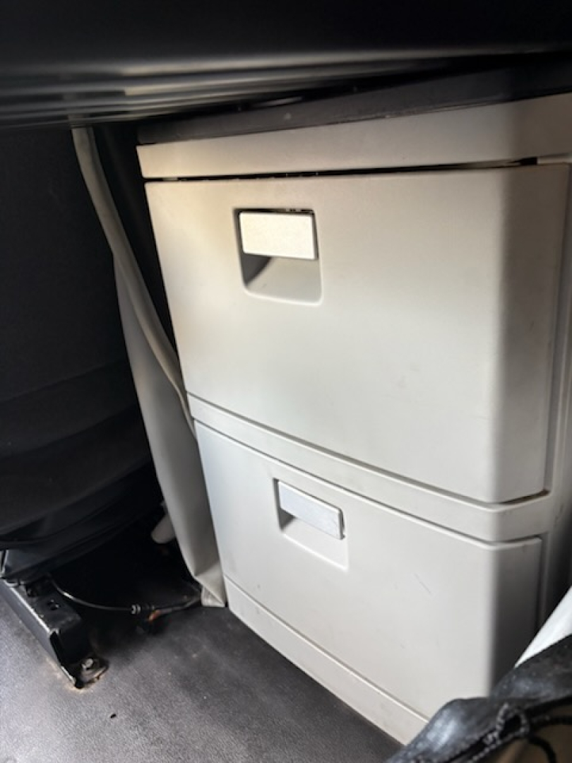 Kenworth T680 cab interior showing two vertical storage drawers unit under dash with light gray color.