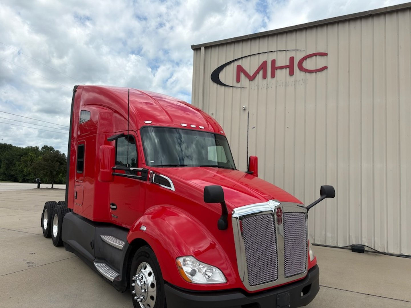 Kenworth T680 2022 red sleeper cab tractor in front of MHC building, side view with chrome grille and large headlights; stock number 0635790, VIN 1XKYD49X8NJ485122.