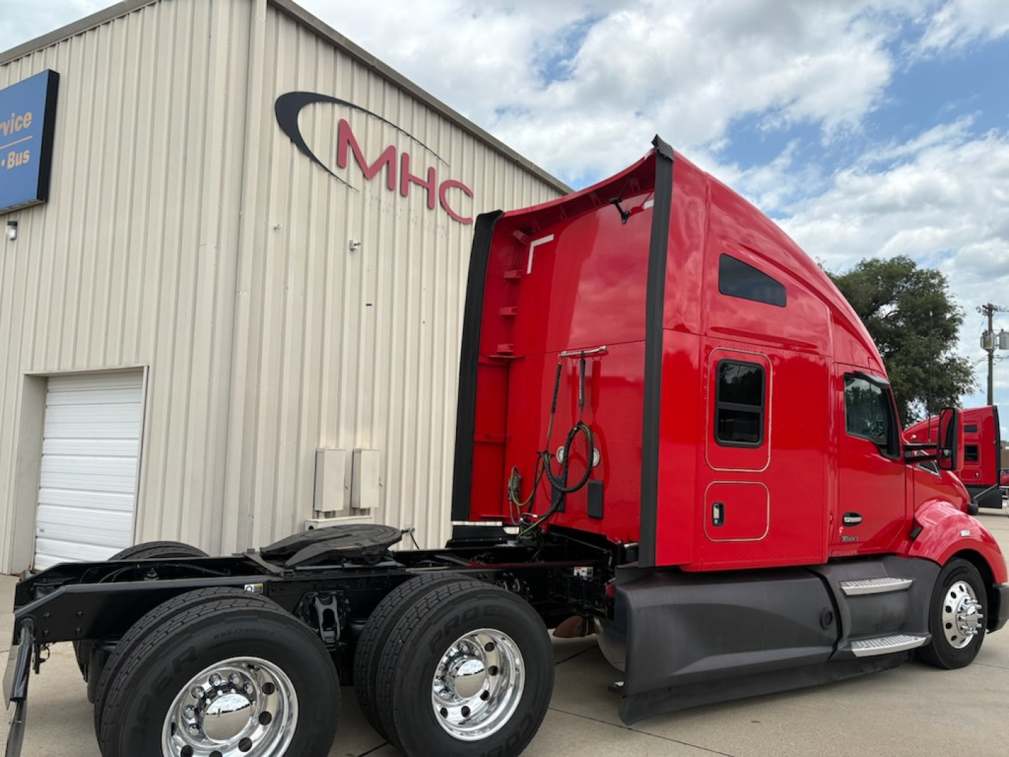 Kenworth T680 tractor with red sleeper cab, dual rear axles, side view showing cab and chassis.