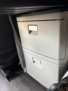 Kenworth T680 cab interior showing two vertical storage drawers unit under dash with light gray color.