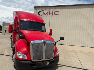 Kenworth T680 conventional sleeper truck in red with large grille and black bumper, front view.